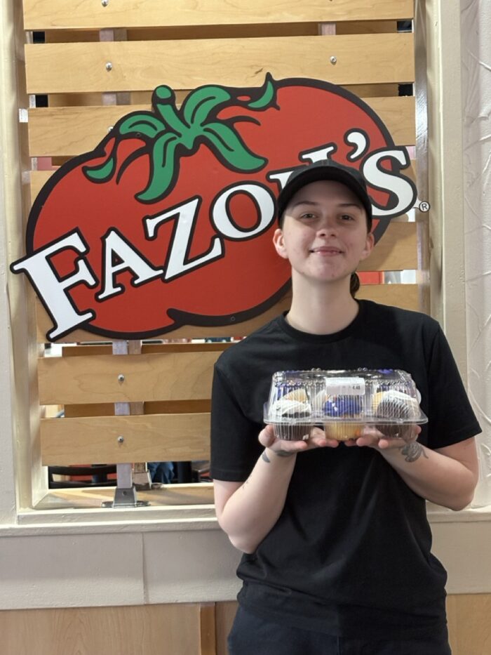 Associate Jada holding cupcakes in front of Fazoli's Sign.